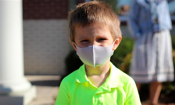 boy smiles while wearing mask